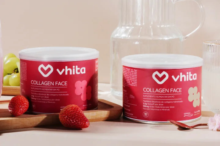 Potes de collagen face Vhita sobre a mesa, com jarra de água e copos, morangos e uvas.